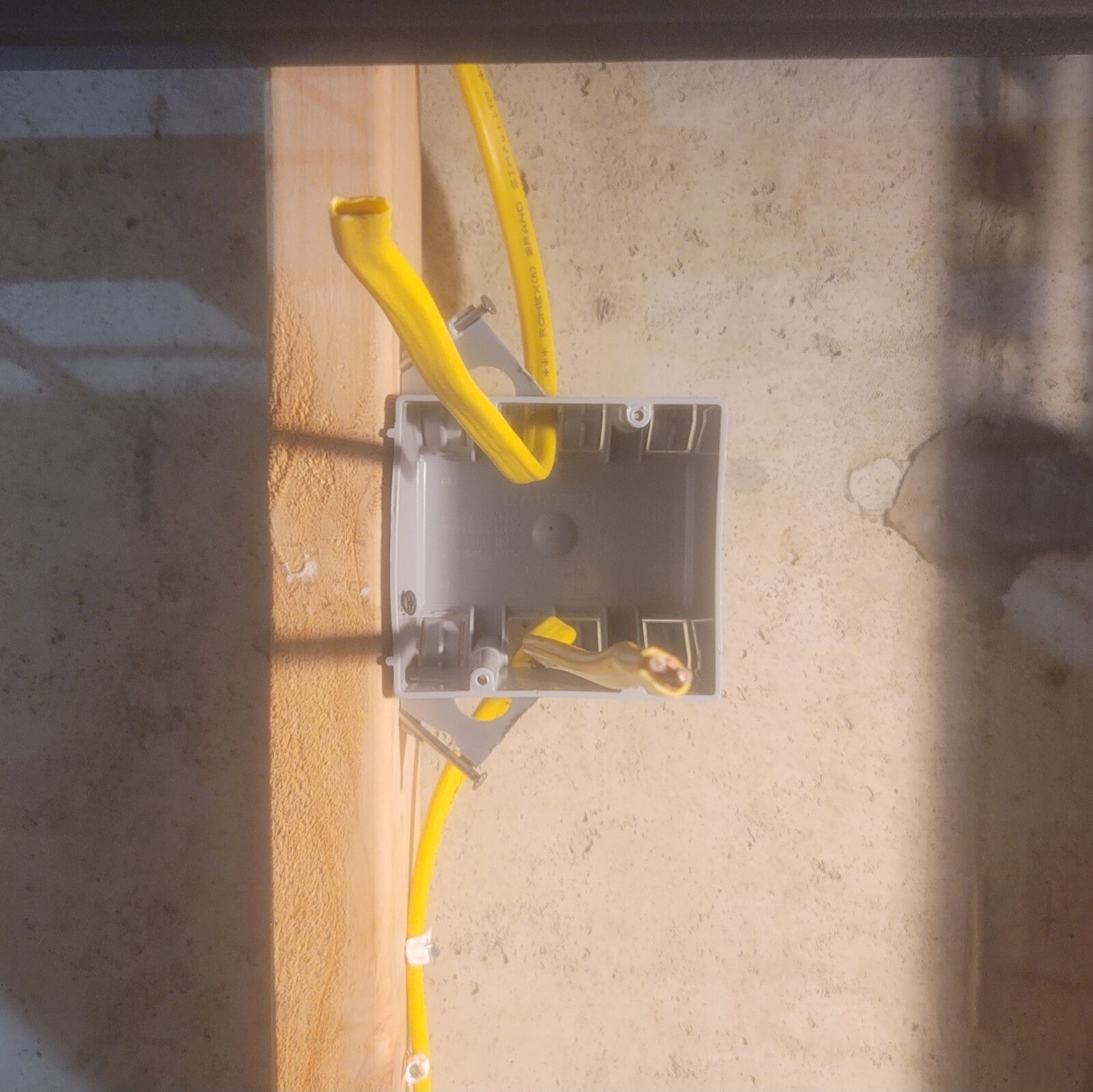 Top two gang box on a stud, yellow cable entering from above & a second run continuing down the stud