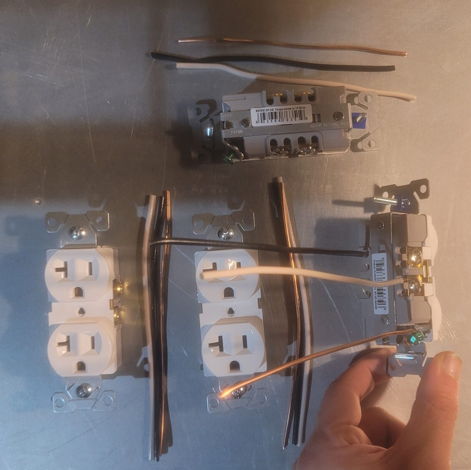 Receptacles laid out on a steel bench with cut black, white & bare copper pigtails