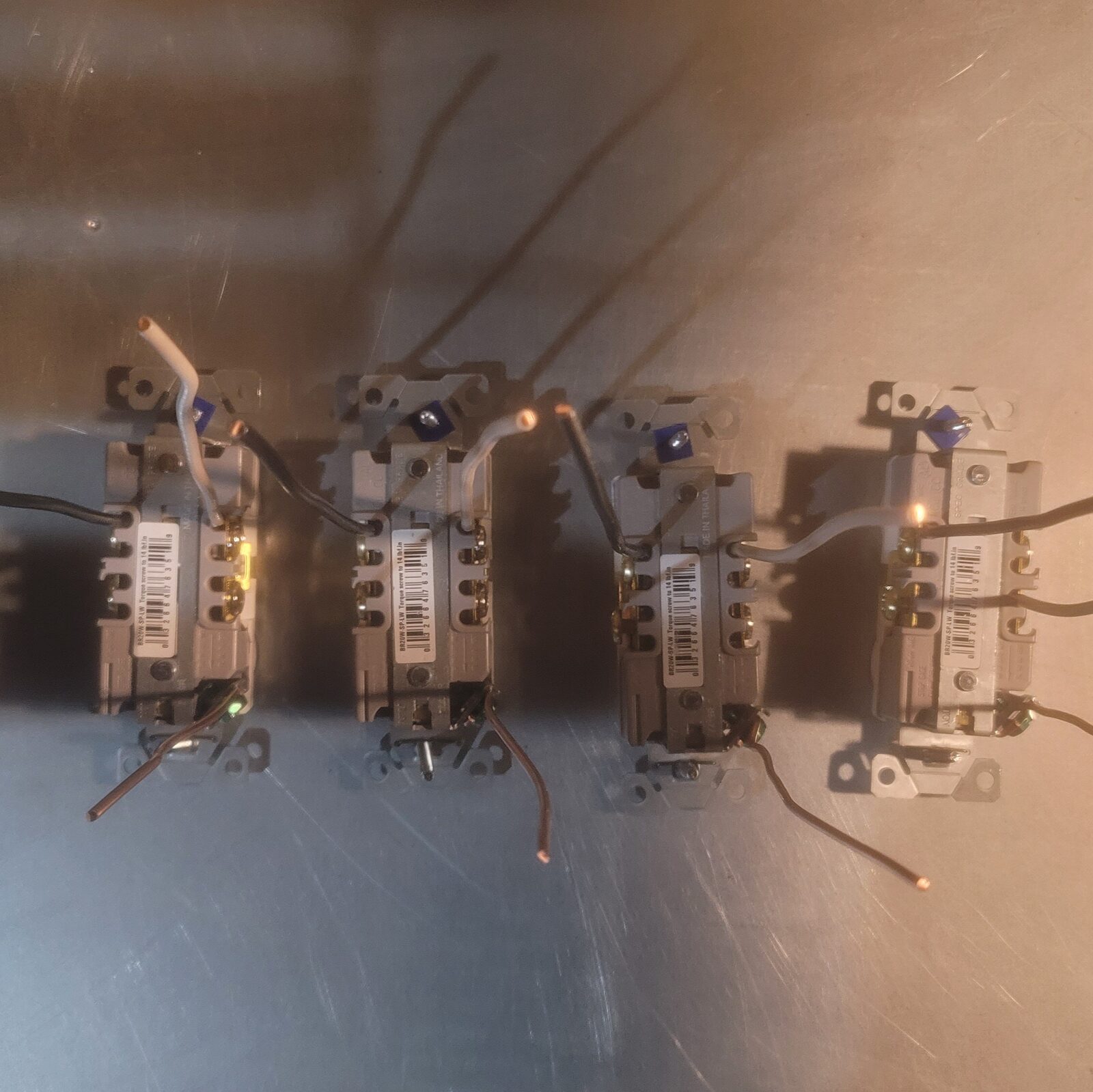 Four receptacles face down on a bench with pigtails clamped into their back wire terminals