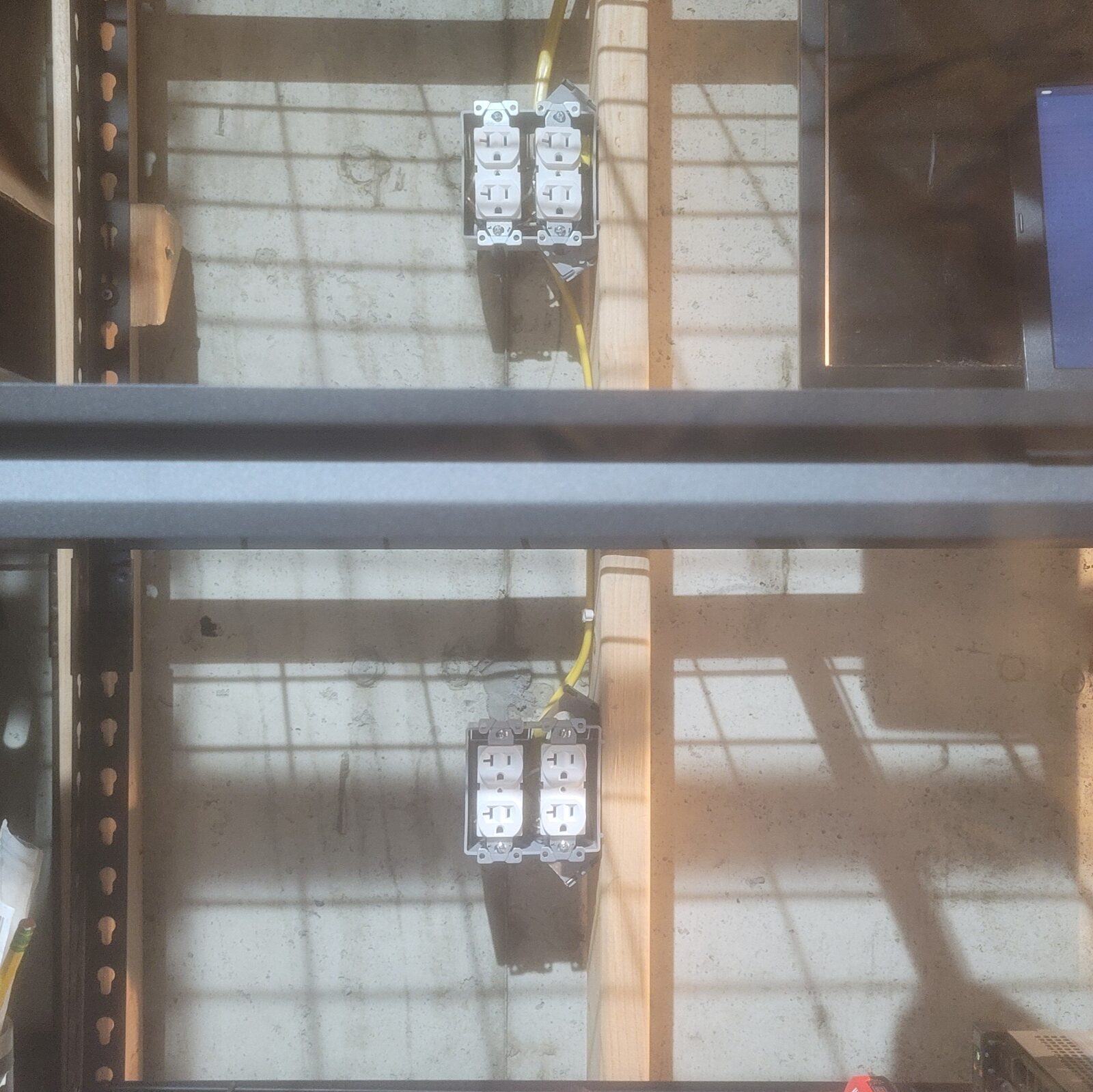 Two finished boxes of 20 amp receptacles stacked on a stud, one per shelf level